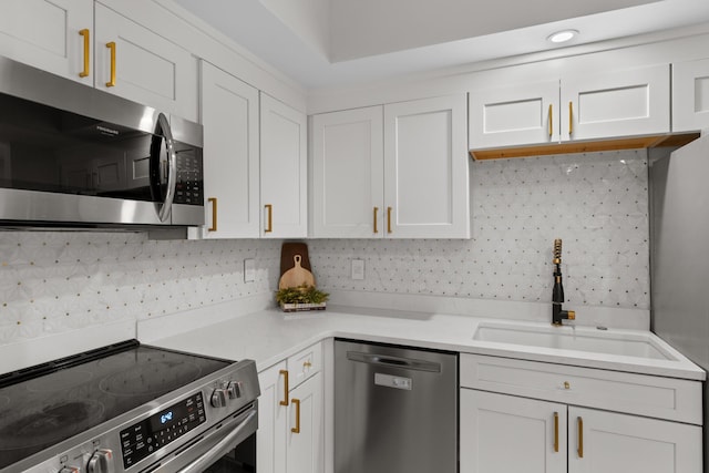 kitchen featuring stainless steel appliances, a sink, white cabinets, light countertops, and tasteful backsplash