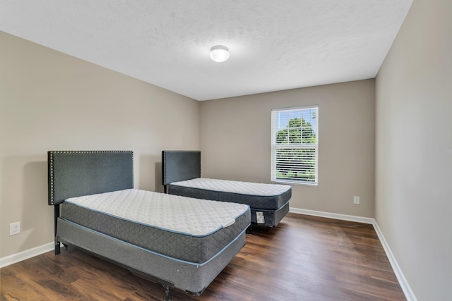 bedroom featuring a textured ceiling, dark wood finished floors, and baseboards