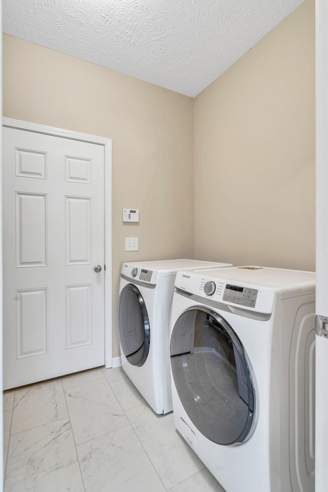 clothes washing area featuring laundry area, marble finish floor, a textured ceiling, and separate washer and dryer