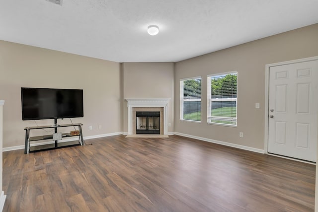 unfurnished living room featuring wood finished floors, a fireplace with flush hearth, visible vents, and baseboards