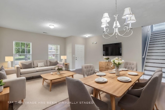 dining space featuring a chandelier, stairway, and visible vents