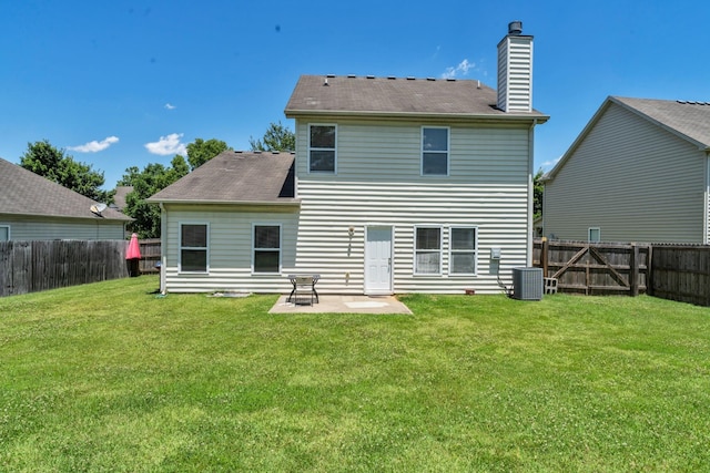 rear view of house with a yard, a chimney, a fenced backyard, and central air condition unit