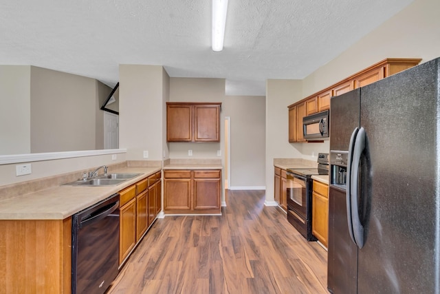 kitchen featuring black appliances, dark wood-style floors, brown cabinetry, and a sink