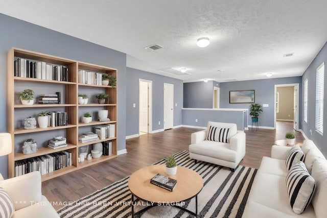 living area with visible vents, a textured ceiling, wood finished floors, and attic access