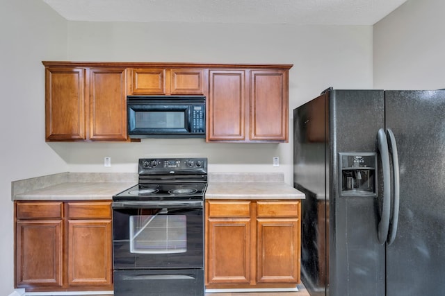 kitchen featuring black appliances, light countertops, and brown cabinetry