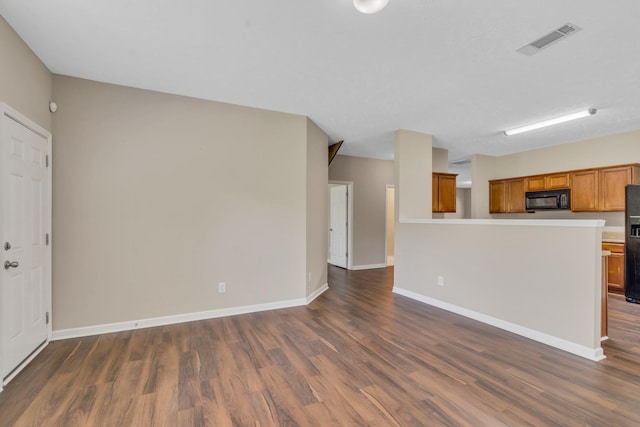 unfurnished living room with dark wood finished floors, visible vents, and baseboards