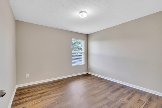 unfurnished room featuring a textured ceiling, wood finished floors, and baseboards