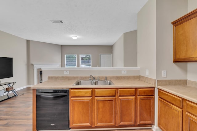 kitchen featuring black dishwasher, brown cabinetry, wood finished floors, light countertops, and a sink