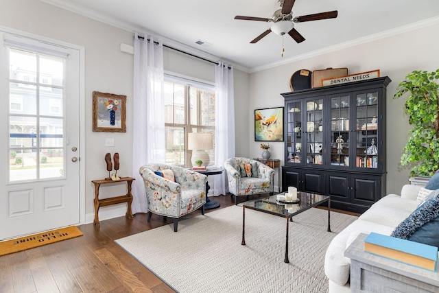 living room featuring ceiling fan, wood finished floors, visible vents, and crown molding