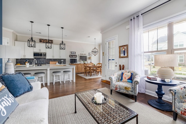 living room featuring baseboards, ornamental molding, dark wood-style flooring, and a healthy amount of sunlight