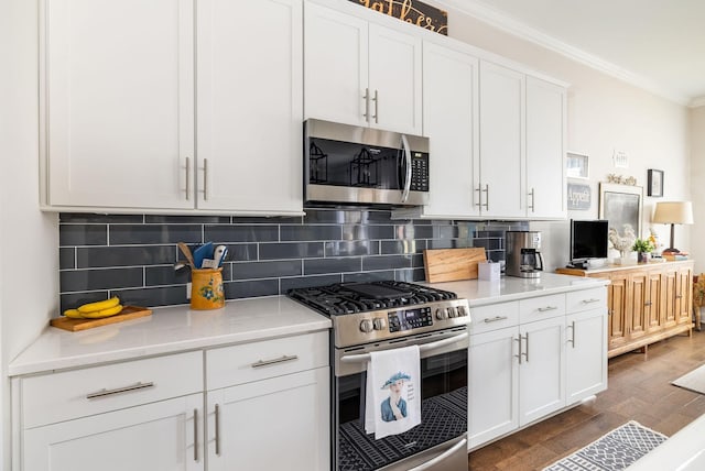 kitchen featuring stainless steel appliances, ornamental molding, dark wood-type flooring, and backsplash