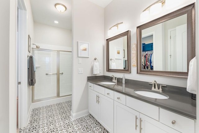 bathroom featuring double vanity, a stall shower, and a sink