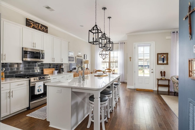 kitchen with stainless steel appliances, tasteful backsplash, visible vents, ornamental molding, and a sink