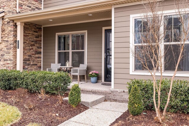 property entrance with covered porch and stone siding