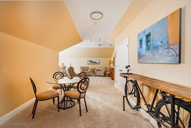 dining area with light colored carpet, vaulted ceiling, and baseboards