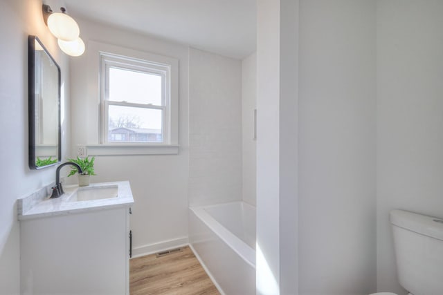 full bathroom featuring visible vents, toilet, vanity, wood finished floors, and a bath