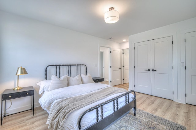 bedroom with a closet, light wood-style flooring, and baseboards