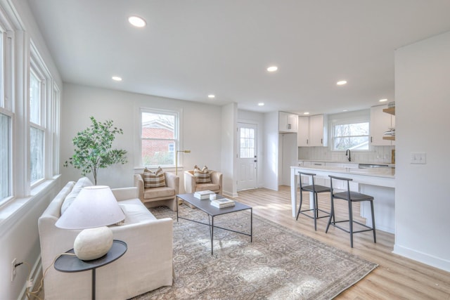 living room with light wood-type flooring, baseboards, and recessed lighting