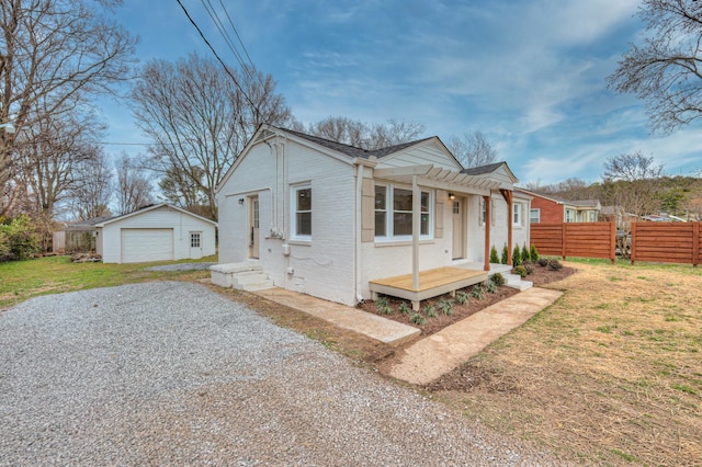 bungalow-style house featuring brick siding, fence, a garage, driveway, and an outdoor structure