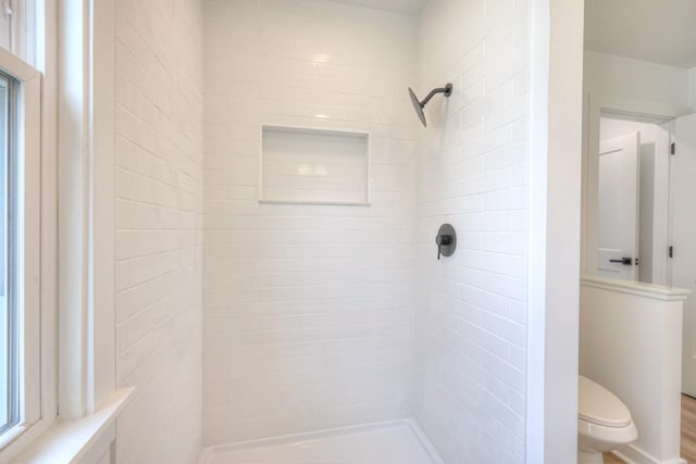 bathroom featuring a tile shower and toilet