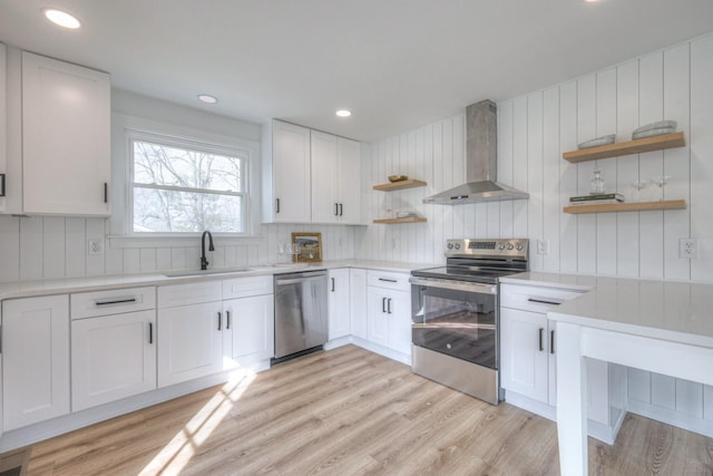 kitchen with light wood-style floors, stainless steel appliances, wall chimney range hood, open shelves, and a sink