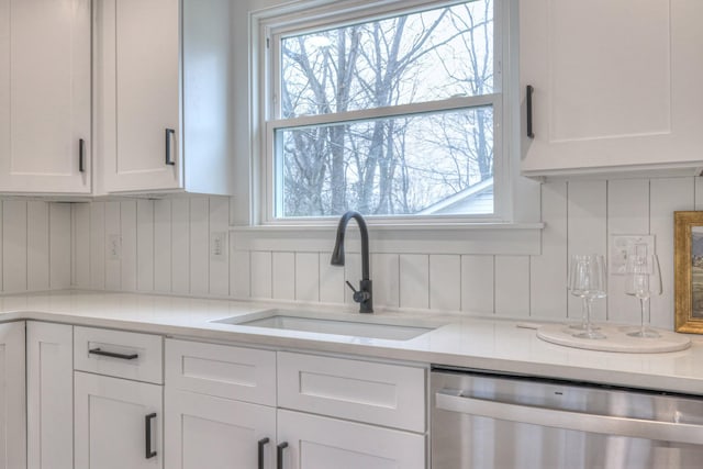 kitchen featuring dishwasher, light countertops, a sink, and white cabinetry