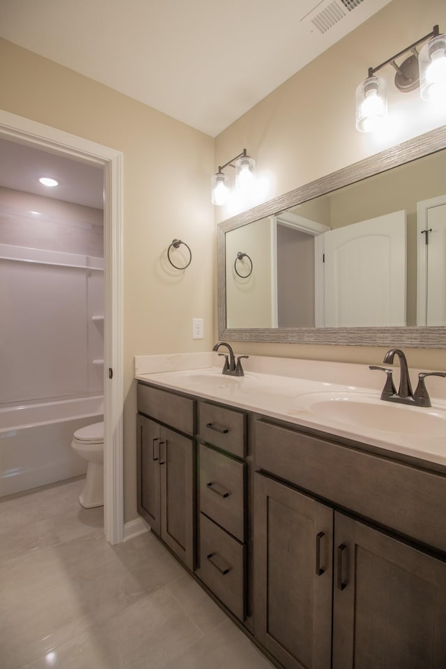 bathroom with double vanity, visible vents, toilet, and a sink