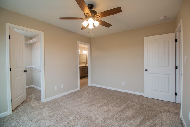 unfurnished bedroom with a closet, baseboards, light colored carpet, and a spacious closet