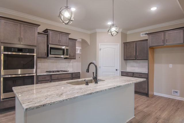 kitchen with visible vents, a sink, arched walkways, appliances with stainless steel finishes, and dark brown cabinets