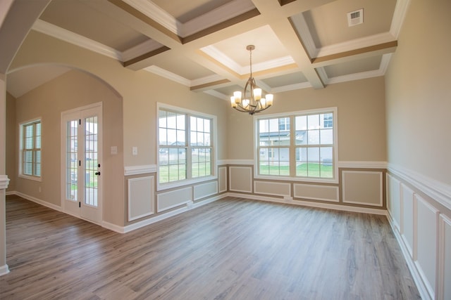 unfurnished dining area featuring wood finished floors, visible vents, an inviting chandelier, arched walkways, and beamed ceiling