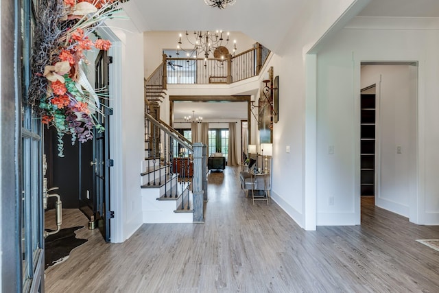 foyer featuring a chandelier, stairs, baseboards, and wood finished floors