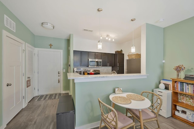 kitchen with appliances with stainless steel finishes, visible vents, dark wood-type flooring, and tasteful backsplash