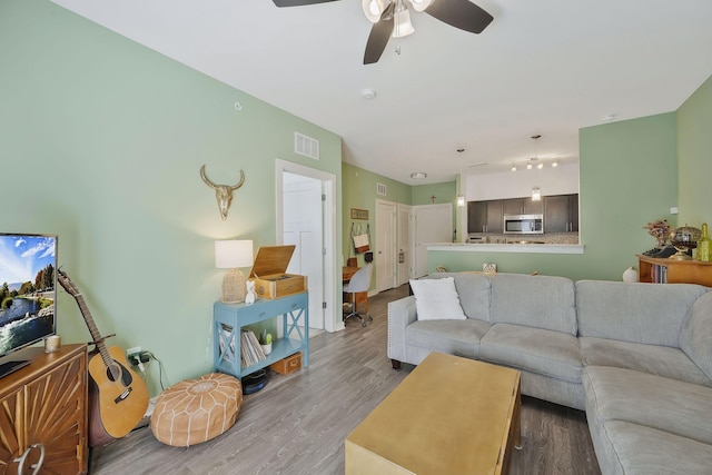 living area featuring ceiling fan, wood finished floors, and visible vents