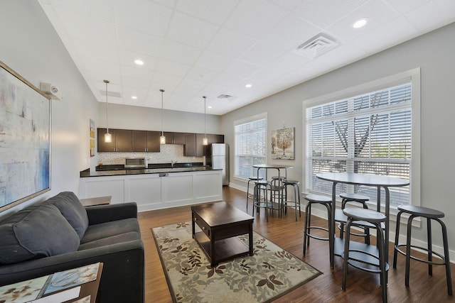 living area with a paneled ceiling, baseboards, visible vents, and dark wood-style flooring