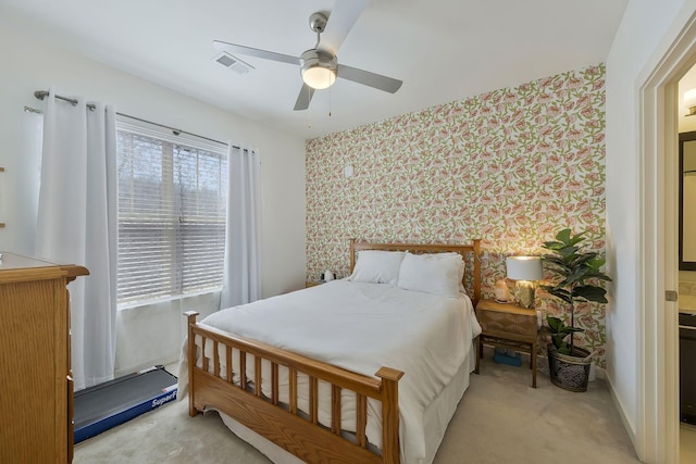 bedroom featuring light colored carpet, visible vents, a ceiling fan, baseboards, and wallpapered walls