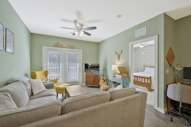 living area with baseboards, ceiling fan, visible vents, and wood finished floors