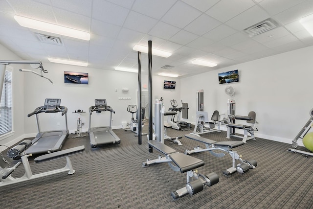 workout area featuring visible vents, a drop ceiling, and baseboards