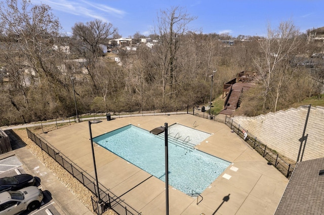 community pool with a patio area and fence