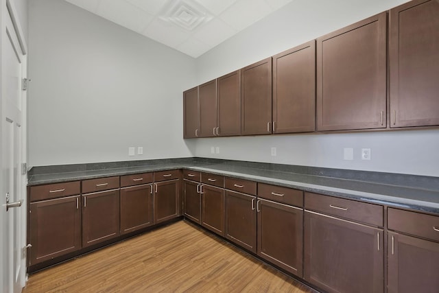 kitchen featuring dark countertops, light wood finished floors, and dark brown cabinets