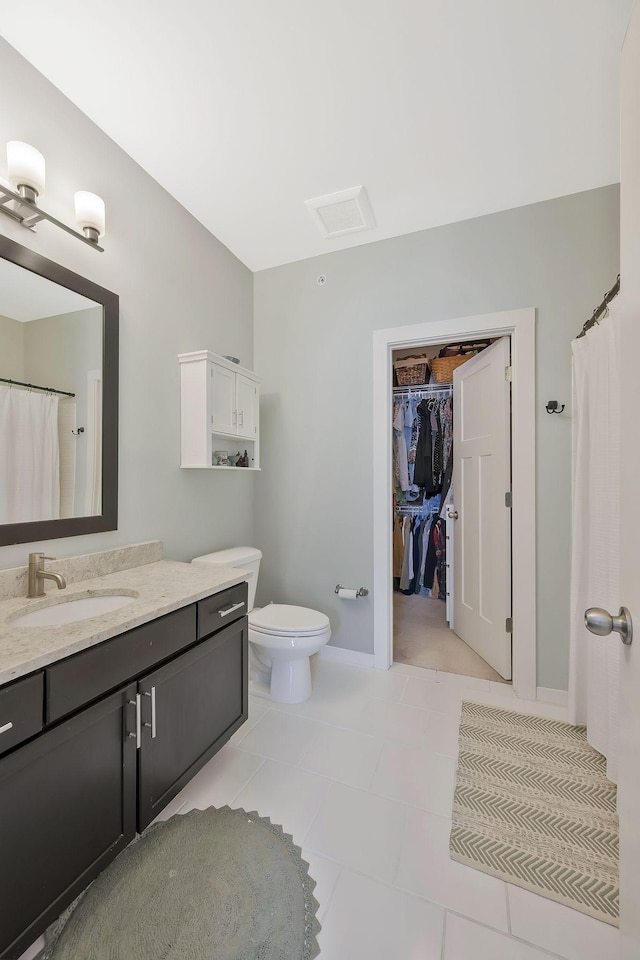 full bathroom with visible vents, toilet, tile patterned flooring, a spacious closet, and vanity