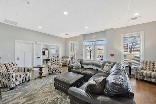 living area with a drop ceiling, wood finished floors, visible vents, and recessed lighting