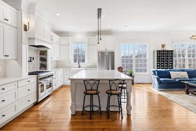 kitchen with open floor plan, a breakfast bar, high end appliances, and white cabinetry