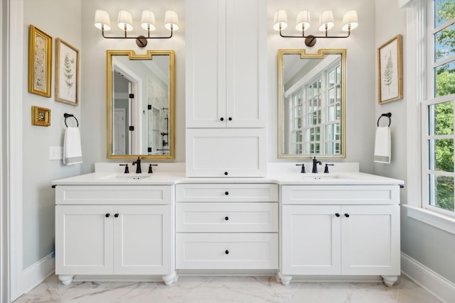 full bath with double vanity, marble finish floor, and a sink