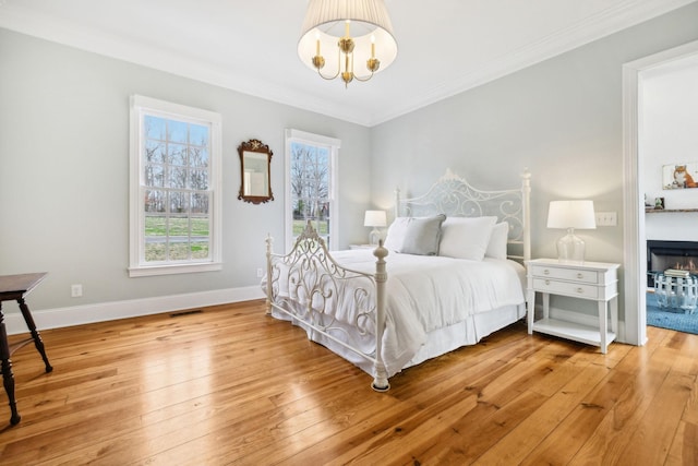 bedroom featuring a notable chandelier, visible vents, ornamental molding, light wood-type flooring, and baseboards