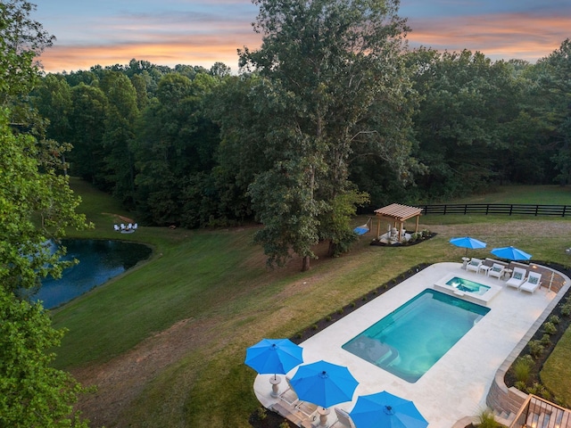 pool at dusk featuring a fenced in pool, a patio, an in ground hot tub, fence, and a yard