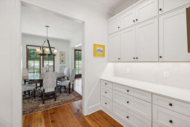 dining space with a notable chandelier, light wood finished floors, baseboards, and crown molding