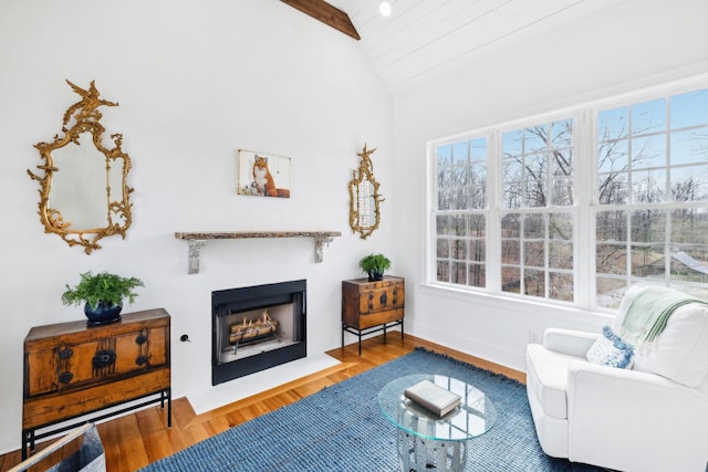 sitting room with a fireplace with flush hearth, lofted ceiling, baseboards, and wood finished floors