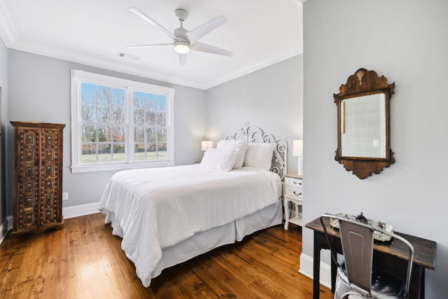 bedroom featuring ceiling fan, wood finished floors, visible vents, baseboards, and ornamental molding