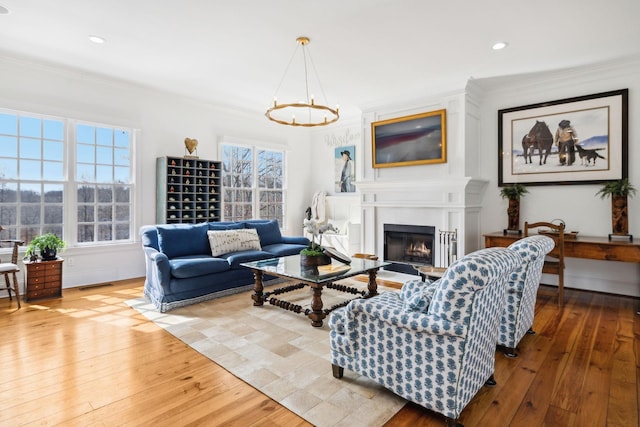 living room with ornamental molding, a fireplace, visible vents, and light wood-style floors