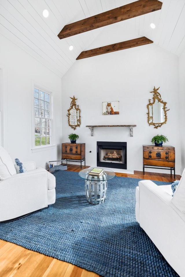 living area featuring a glass covered fireplace, wooden ceiling, lofted ceiling with beams, and wood finished floors